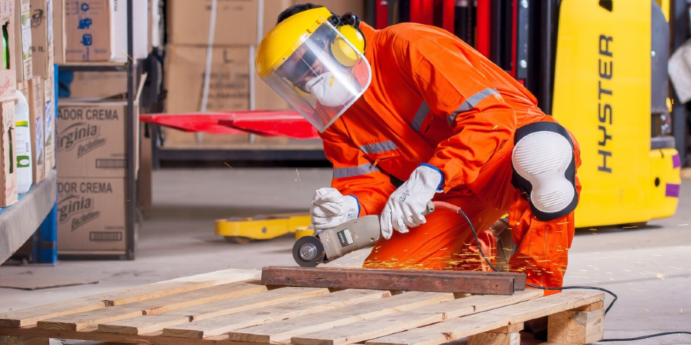 Trabajador con traje de protección cortando metal